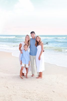 Parents and children laughing together during a family beach photography session at the shore.