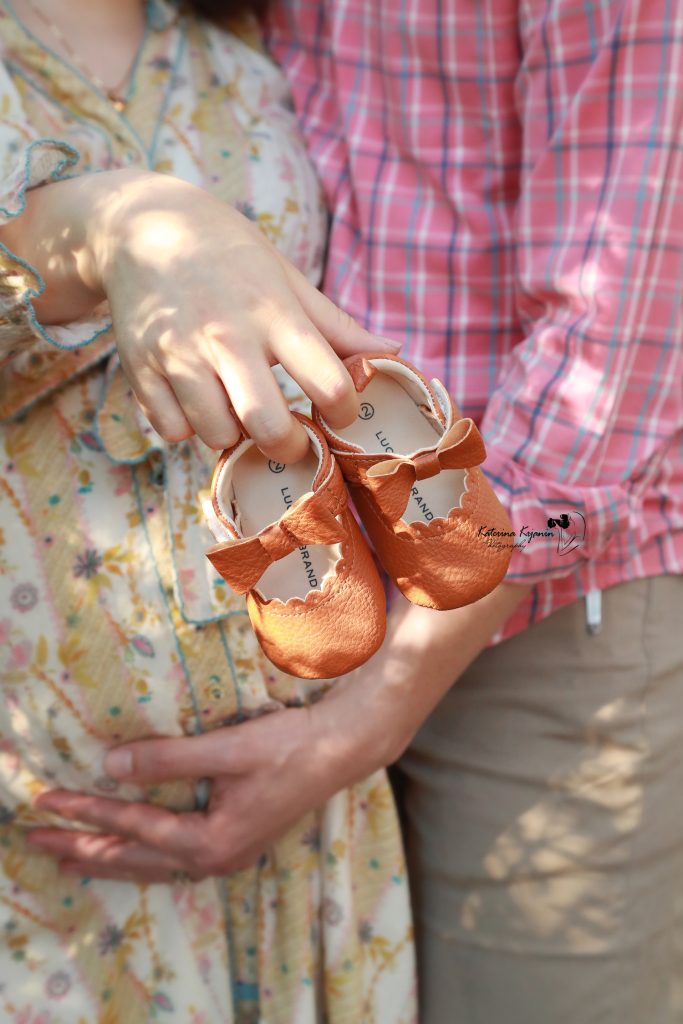 Close-up of a pregnant mother’s hands on her belly, highlighting the beauty and glow of maternity in a professional session.