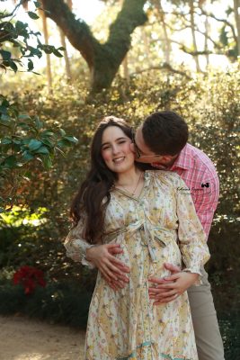 Expectant mother standing in a serene garden, captured in a natural and elegant maternity photoshoot by Katerina Krjanina.