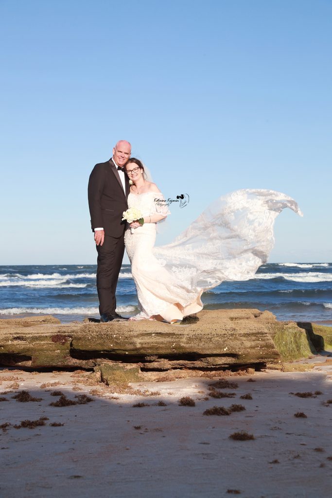 Bride and groom standing together on Marineland Beach, Florida, during a romantic beach wedding photography session.